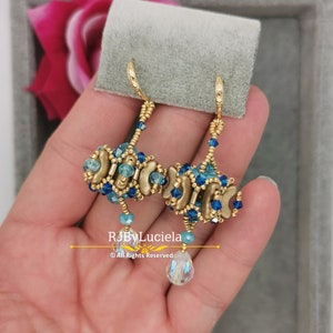 May include: A pair of gold hoop earrings with blue and gold beads. The earrings have a teardrop-shaped crystal hanging from the bottom.