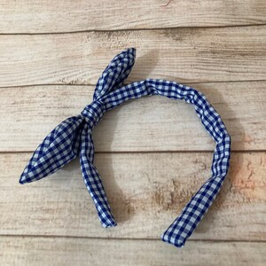 May include: A blue and white gingham headband with a bow on the top.