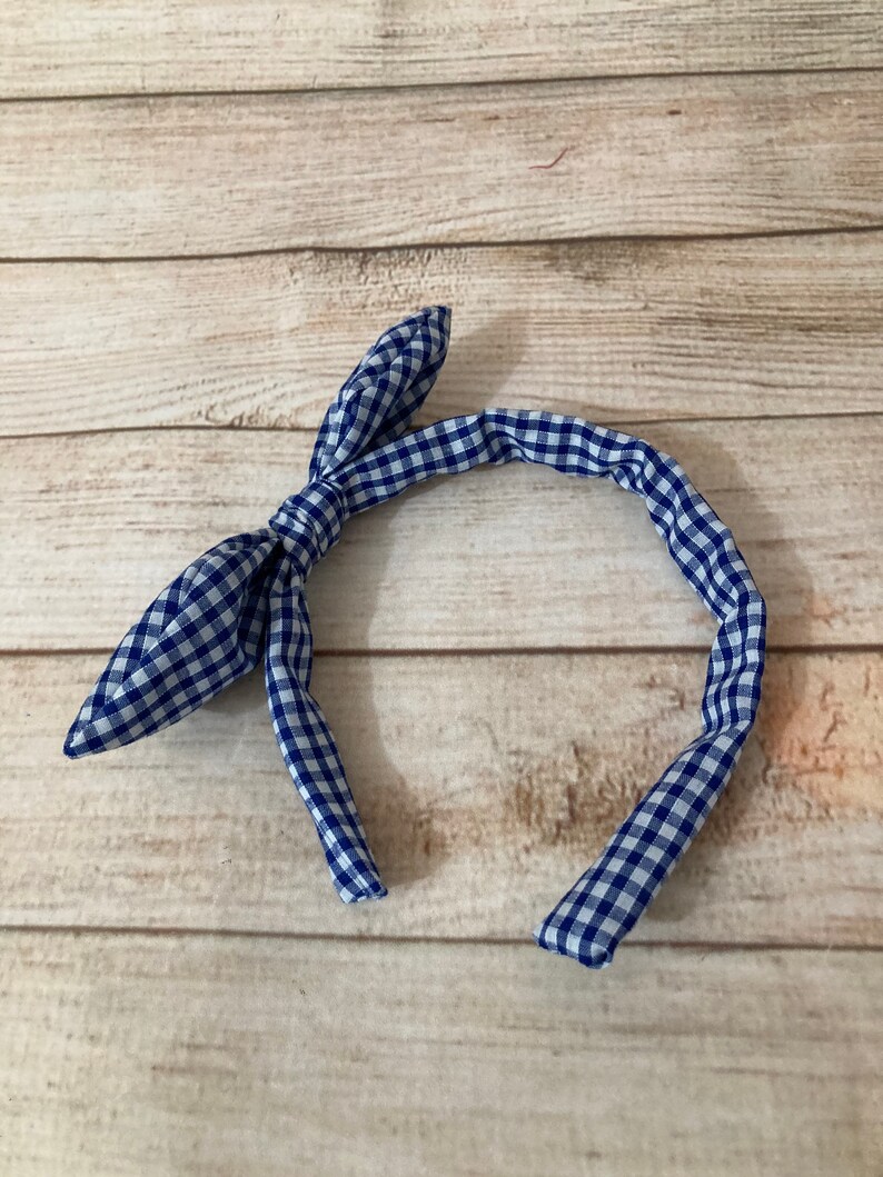 May include: A blue and white gingham headband with a bow on the top.