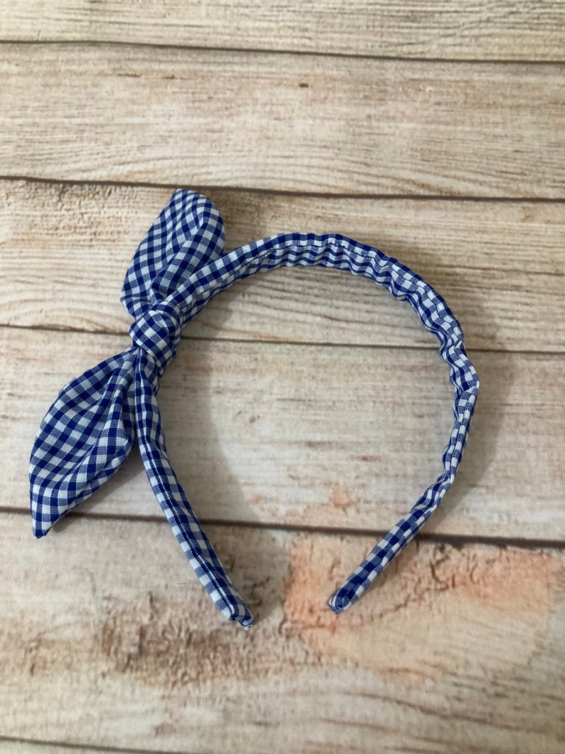 May include: A blue and white gingham headband with a bow on the side.