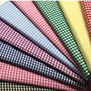 May include: A collection of eight gingham fabrics in various colors, including blue, pink, green, yellow, and purple. The fabrics are arranged in a fan shape, with the lightest color at the top and the darkest color at the bottom.