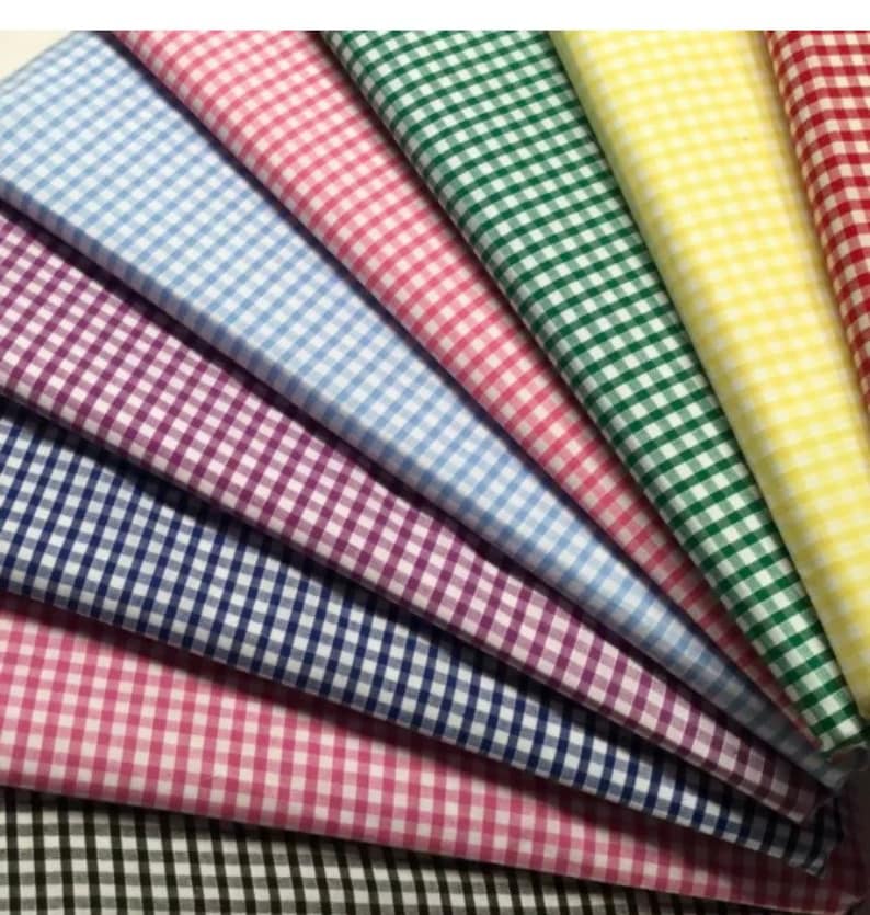 May include: A collection of eight gingham fabrics in various colors, including blue, pink, green, yellow, and purple. The fabrics are arranged in a fan shape, with the lightest color at the top and the darkest color at the bottom.