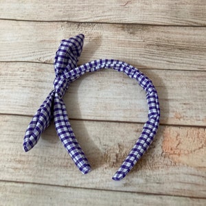May include: Purple and white checkered headband with a bow knot.
