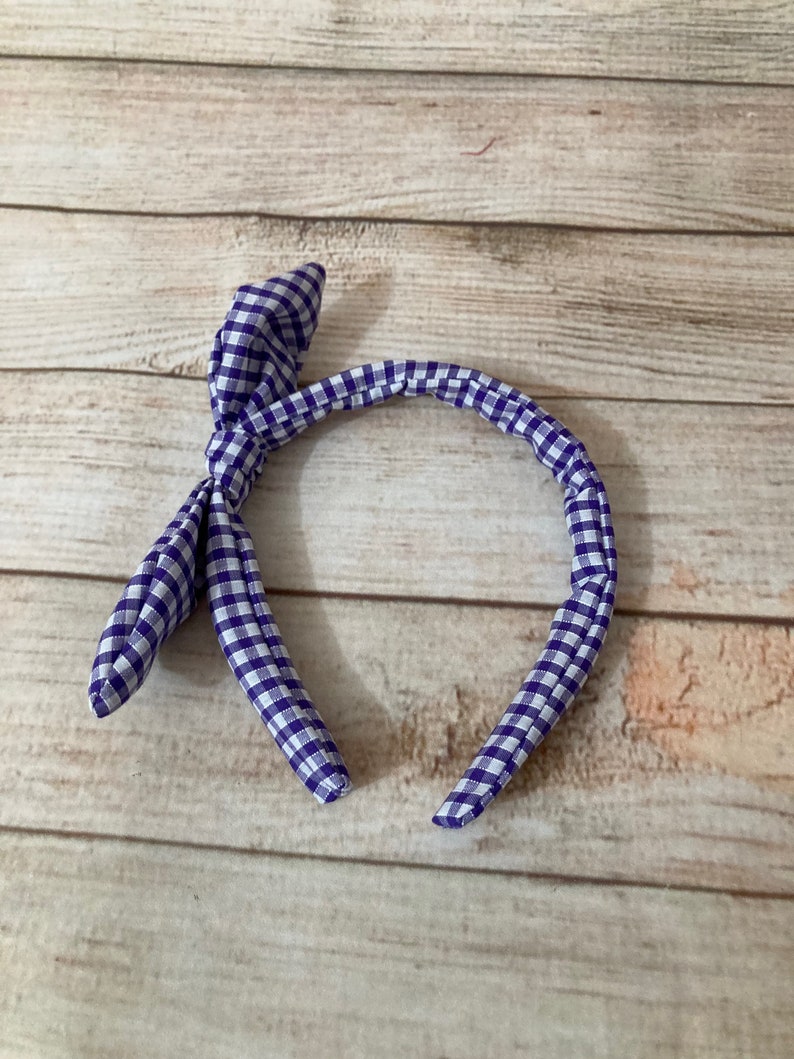 May include: Purple and white checkered headband with a bow knot.