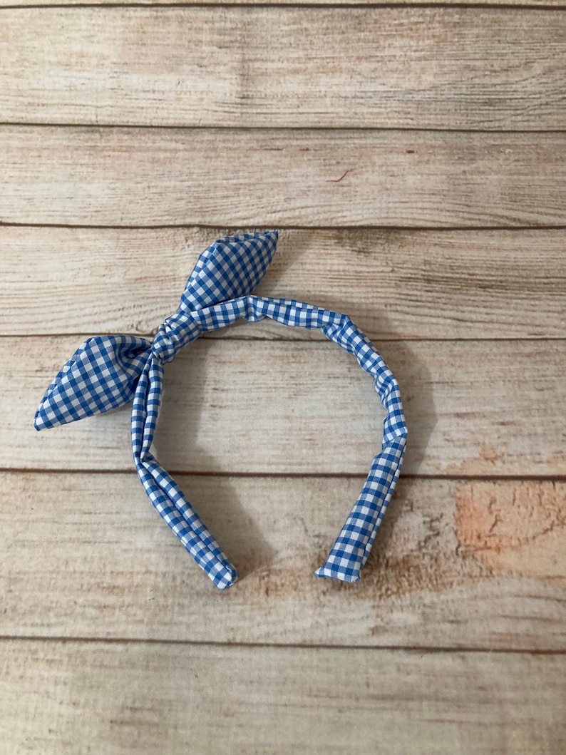 May include: A blue and white gingham headband with a knotted bow.