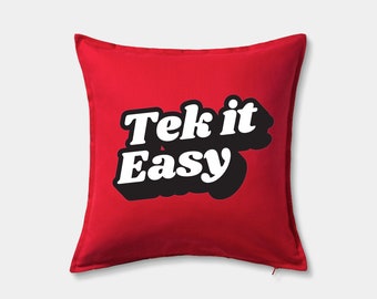 Pode incluir: Travesseiro vermelho com um gráfico preto e branco que diz "Tek it Easy".