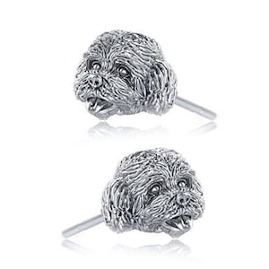 May include: A pair of silver stud earrings featuring a detailed, three-dimensional design of a dog's head. The earrings are a cute and stylish accessory for dog lovers.