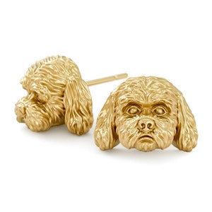 May include: A pair of gold-toned stud earrings featuring a detailed 3D design of a poodle's head. The earrings are a unique and stylish way to show your love for your furry friend.