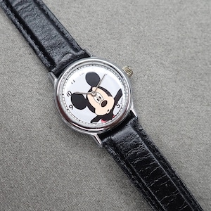 May include: A silver wristwatch with a black leather strap features a white face with a black and white image of Mickey Mouse. The watch face has black Roman numeral hour markers.
