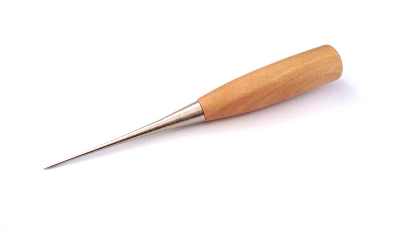 Op de afbeelding: Een leergereedschap met een houten handvat en een scherpe, puntige metalen punt. De priem is ontworpen om leer en andere materialen te doorboren. De punt is zilverkleurig. Een veelgebruikt gereedschap voor naaien en knutselen.