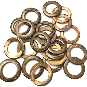 May include: A pile of brown coconut shell rings, each with a smooth, polished surface and a natural wood grain pattern. The rings are approximately 2 inches in diameter and are perfect for crafting projects.