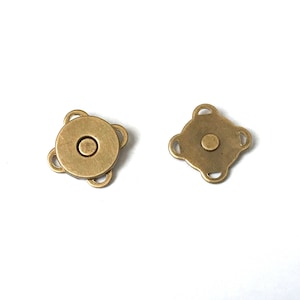 May include: Two antique brass magnetic snap closures. One is round with three loops, the other is square with four loops. Both have a central magnetic stud. Ideal for bags, purses, and other craft projects.