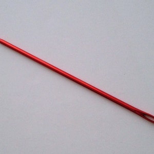Könnte beinhalten: Ein roter Häkelhaken mit einer spitzen Spitze und einer Schlaufe am anderen Ende.