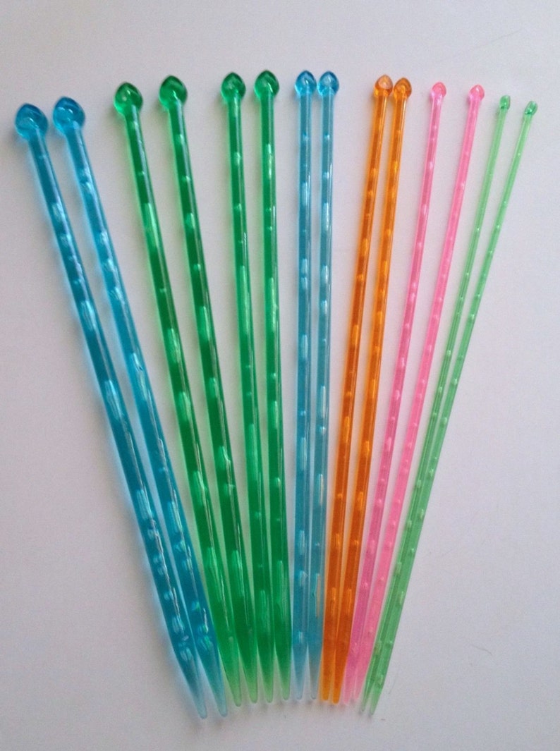 May include: A collection of colorful cocktail stirrers in shades of blue, green, orange, pink, and light green. Each stirrer is approximately 6 inches long, with a rounded top and a textured shaft. The stirrers are arranged in a fan shape.