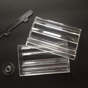 May include: A clear plastic box with a lid. The box has a rectangular shape and is made of clear plastic. The lid is also made of clear plastic and has a rectangular shape.