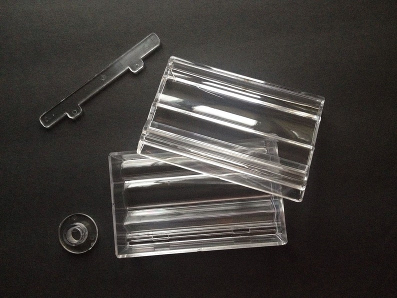 May include: A clear plastic box with a lid. The box has a rectangular shape and is made of clear plastic. The lid is also made of clear plastic and has a rectangular shape.