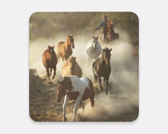 Cowboy driving horses in dust; western art on a drink coaster