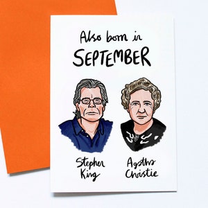 May include: A white greeting card with the text "Also born in SEPTEMBER" and illustrations of Stephen King and Agatha Christie. The card is paired with an orange envelope.