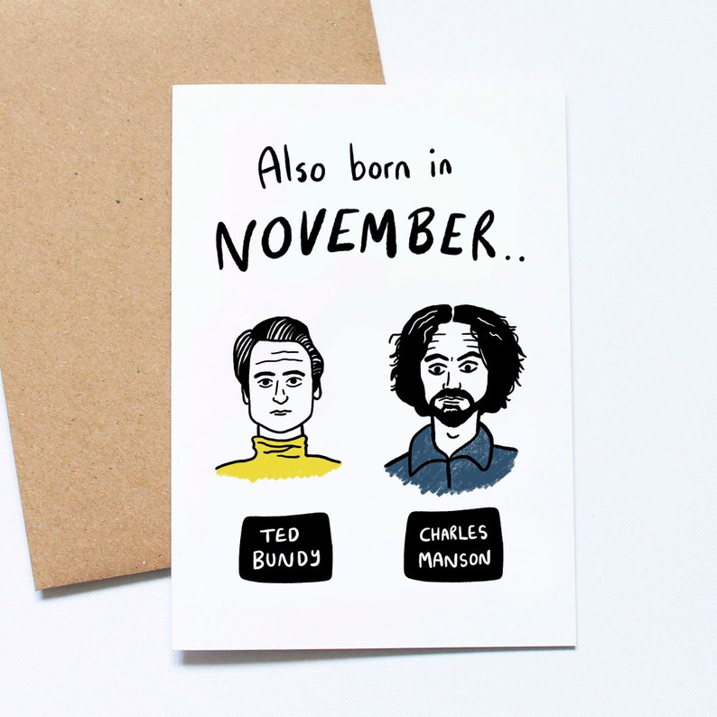 May include: A white greeting card with the text "Also born in NOVEMBER.." and illustrations of Ted Bundy and Charles Manson. The card is paired with a brown envelope.