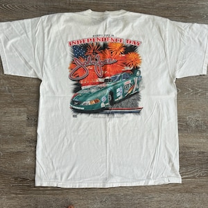 May include: White t-shirt with a green race car and fireworks graphic. The text "Every day is Independence Day" is printed on the shirt.