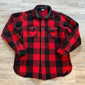 May include: A red and black flannel shirt with a button-up front and two chest pockets.