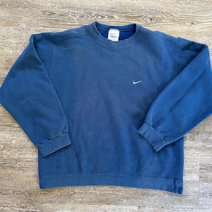 May include: A blue crew neck sweatshirt with a white Nike swoosh logo on the front.