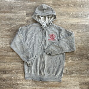 May include: A gray zip-up hoodie with a red embroidered logo that says "Cornell University".