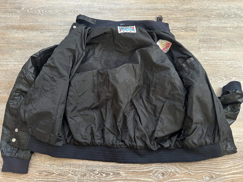 Pode incluir: Uma caneca de cer&acirc;mica branca com uma al&ccedil;a preta e o texto "But First, Coffee" em preto, em negrito. A caneca est&aacute; sobre uma superf&iacute;cie branca.