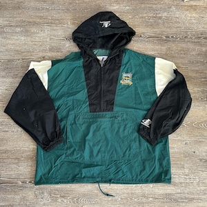 May include: A green, black, and white windbreaker jacket with a drawstring hood. The jacket has a zipper closure and a large pocket on the front. The jacket has a logo on the left chest that says "Seattle SuperSonics" and a logo on the right sleeve that says "Champion".