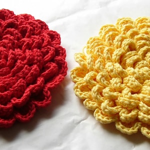 Könnte beinhalten: Zwei gehäkelte Topflappen in Blumenform, einer rot und einer gelb.