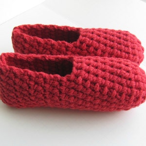 May include: A pair of red crocheted slippers. The slippers are made with a simple stitch and have a flat sole.