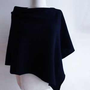 Pode incluir: Um poncho azul marinho com gola alta e uma bainha ligeiramente assimétrica.