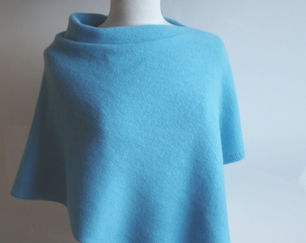 Puede incluir: Un poncho de punto azul claro con un escote drapeado.
