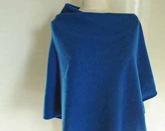 May include: A vibrant blue poncho-style wrap displayed on a mannequin. The wrap is made of a soft, possibly knitted material, and drapes over the shoulders. The color is a rich, saturated blue, and the edges appear to be finished with a simple hem.
