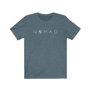 Puede incluir: Una camiseta azul oscuro con un gr&aacute;fico blanco de la palabra "NOMAD" con un icono de globo terr&aacute;queo que reemplaza la "O".