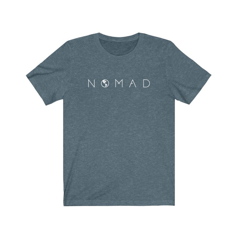 Puede incluir: Una camiseta azul oscuro con un gr&aacute;fico blanco de la palabra "NOMAD" con un icono de globo terr&aacute;queo que reemplaza la "O".