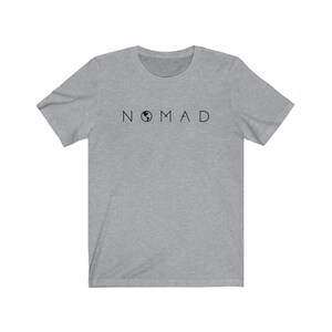 Puede incluir: Una camiseta gris jaspeada con un gr&aacute;fico negro de un globo terr&aacute;queo y la palabra "NOMAD" impresa en la parte delantera.