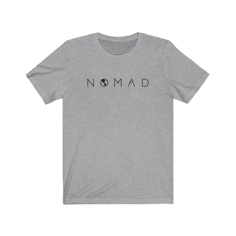Puede incluir: Una camiseta gris jaspeada con un gr&aacute;fico negro de un globo terr&aacute;queo y la palabra "NOMAD" impresa en la parte delantera.