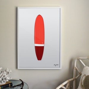 May include: A framed print of a red and white surfboard with a white background. The surfboard is a longboard style with a rounded nose and a single fin.