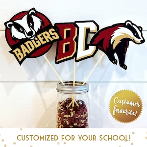 May include: Three table centerpieces featuring a red and gold badger mascot, the letters "BC" in red and gold, and a red and gold badger mascot. The centerpieces are in a clear glass jar with red and gold confetti. The text "Customer favorite!" is on a gold sticker.