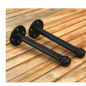 May include: Two black metal shelf brackets with a pipe design. The brackets are 10 inches long and have a 3-inch diameter flange.