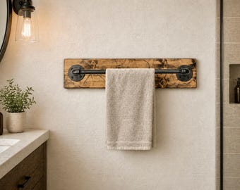May include: A rustic wooden towel rack with a black metal bar and fittings. A beige towel hangs from the bar. The rack is mounted on a light-colored wall, creating a contrast with the dark metal and wood.