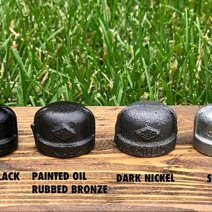 May include: Four metal pipe caps in different finishes: painted black, painted oil rubbed bronze, dark nickel, and silver. The caps have a diamond-shaped design.