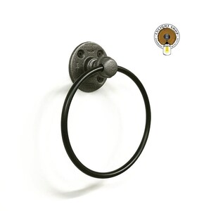 May include: Black metal towel ring with a round base and a pipe fitting design. The ring is attached to a white wall.