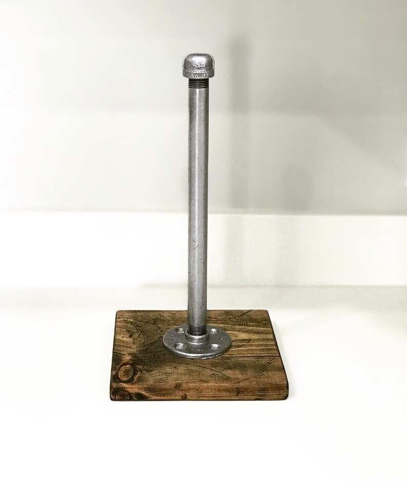 Puede incluir: Un porta rollo de papel de cocina de metal plateado con una base de madera. La base est&aacute; hecha de madera recuperada y tiene un aspecto r&uacute;stico.