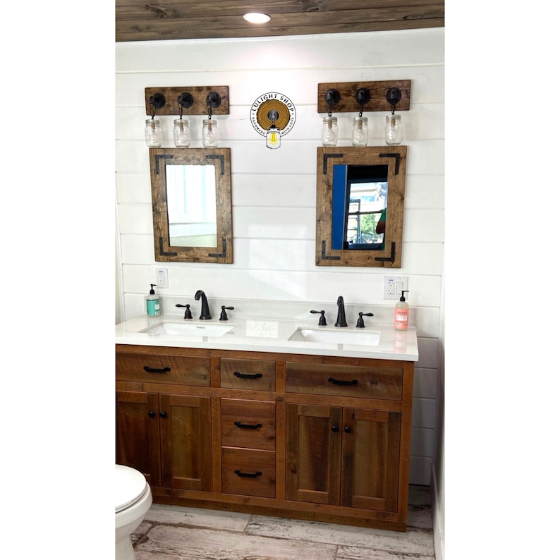 May include: A double bathroom vanity with a wooden cabinet, white countertop, and two rectangular mirrors. Above each mirror is a wooden light fixture with three glass mason jar shades. A logo reads LULIGHT SHOP HANDMADE WITH LOVE.