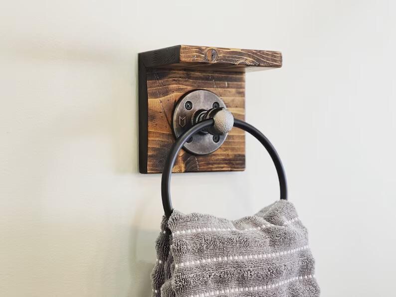 black pipe towel ring on rustic wood board with a small shelf for storage