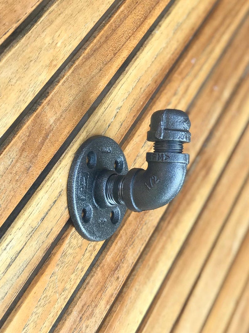 May include: A black metal pipe hook next to an entry for jackets, scarves, backpacks, hats hanging.