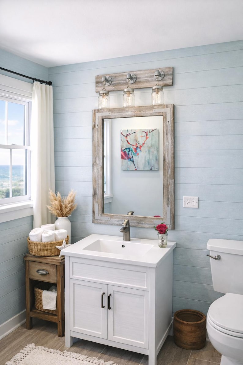 Handcrafted wood framed mirror mounted on a bathroom vanity wall with a three mason jar vanity light fixture on top, featuring a whitewash finish and natural wood grain for a farmhouse-style charm