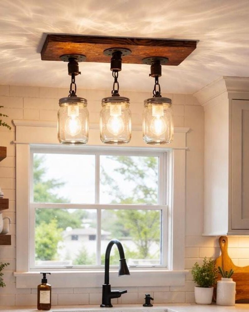 Farmhouse mason jar pendant light fixture with wood beam and chains hanging above rustic dining table in cozy kitchen